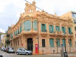 Fachada completa del edificio en esquina con detalles arquitectónicos y coches aparcados