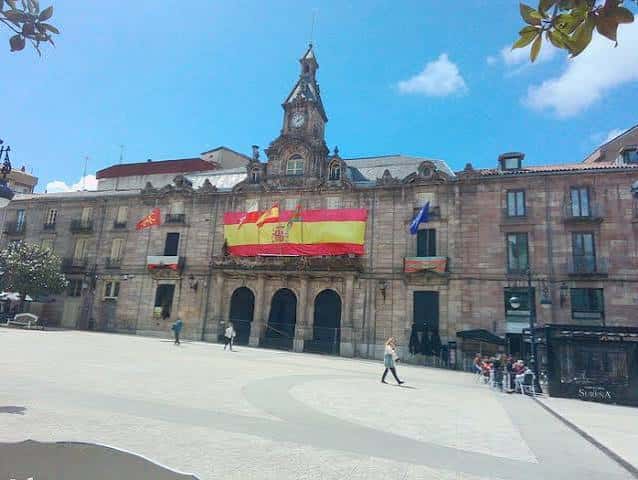 Plaza principal del barrio con edificio histórico y banderas españolas europeas