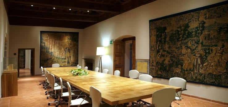 Sala de eventos en el palacio con mesa larga, tapices históricos y iluminación cálida