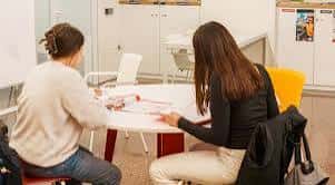 Sesión de trabajo colaborativo entre dos jóvenes en una sala interior