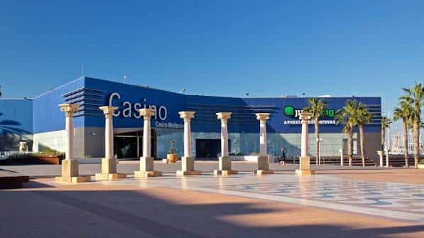 Vista exterior del casino durante el día con columnas decorativas y palmeras