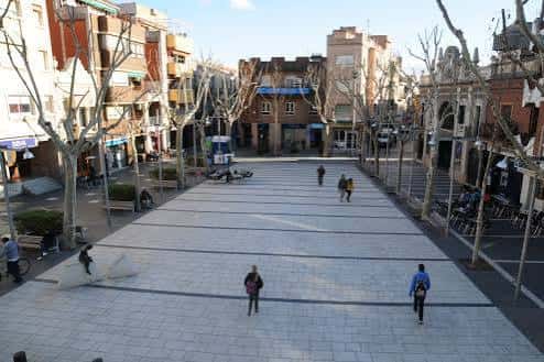 Plaza amplia con adoquines y personas caminando bajo el sol