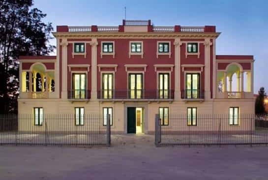 Fachada iluminada de la casa principal del Parc de Mas Iglésias al atardecer
