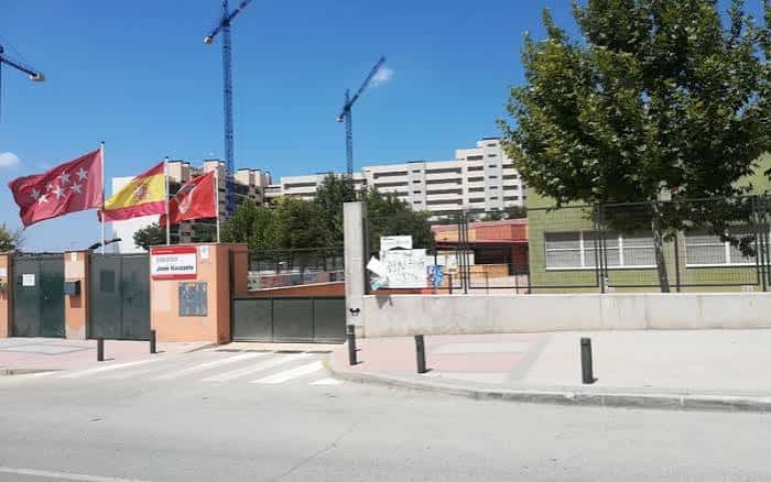 Vista exterior del CEIP José Iturzaeta con banderas y grúas de fondo