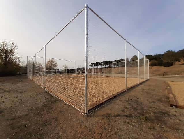 Pista deportiva cerrada con valla metálica y superficie de tierra