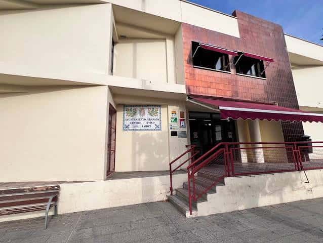 Entrada principal del edificio con rampa de acceso y marquesina roja