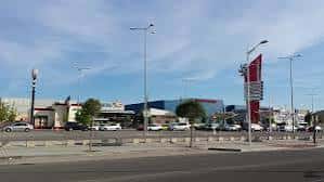 Exterior del centro comercial visto desde la carretera principal, mostrando el aparcamiento y la señalización