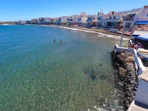 Agua cristalina frente a la playa con edificios blancos característicos de Telde