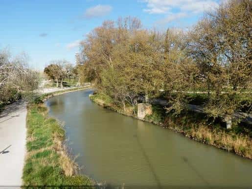 Curva del canal rodeada de vegetación y senderos peatonales