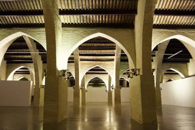 Interior de las Reals Atarazanes con bóvedas de ladrillo y columnas iluminadas