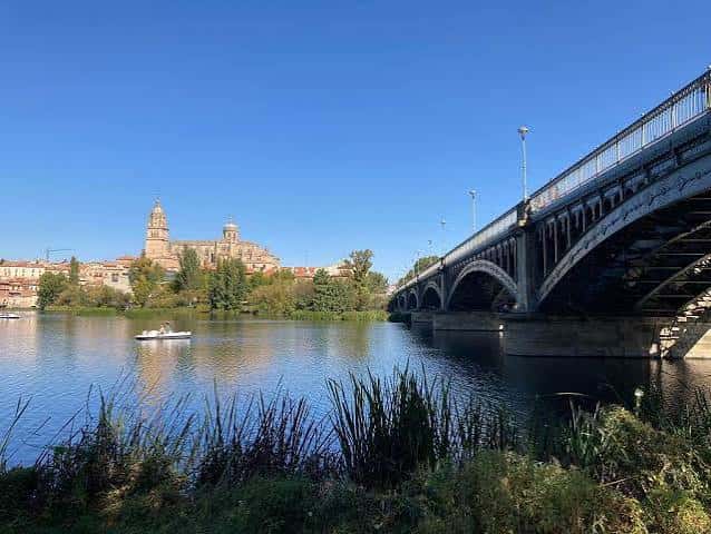El Puente Romano y la Catedral reflejados en las aguas del río Tormes bajo un cielo despejado
