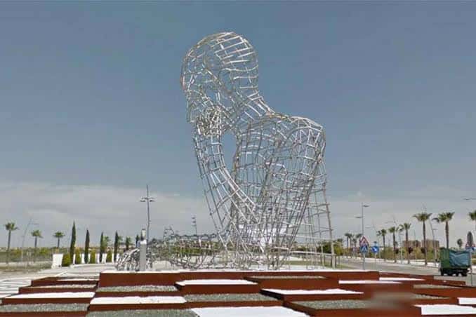 Escultura del Pensador en Dos Hermanas rodeada de palmeras y césped bajo un cielo despejado