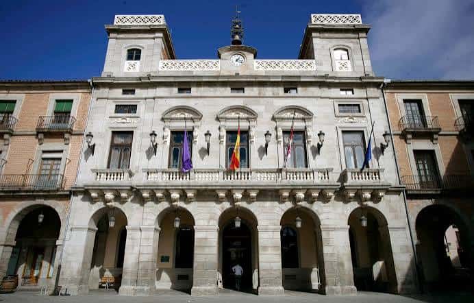 Fachada principal del Ayuntamiento de Ávila con arcos y banderas en la plaza
