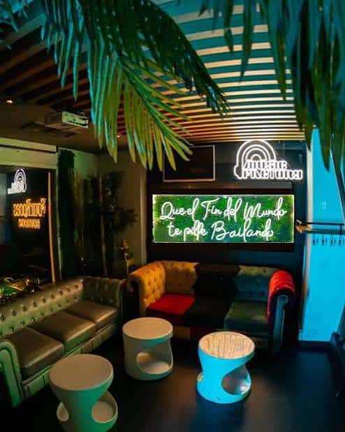Interior del club con sofá amarillo y letrero luminoso