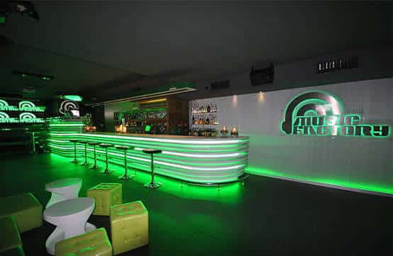 Bar principal con iluminación verde y logo de Music Factory