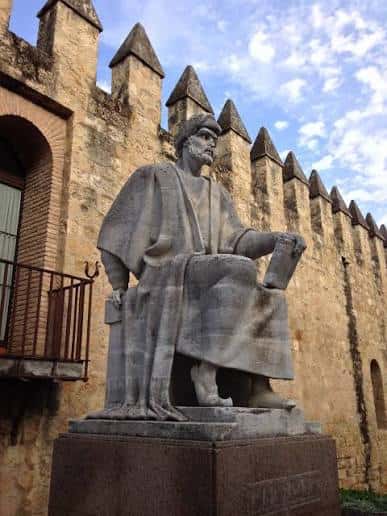 Estatua de Averroes en Córdoba con fondo de muralla almenada