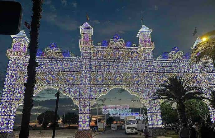 Vista nocturna del arco iluminado con luces decorativas en el recinto ferial