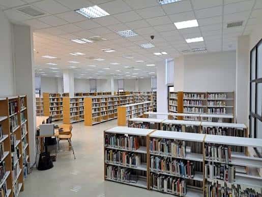 Interior amplio y luminoso de la biblioteca con estanterías organizadas y zonas de lectura