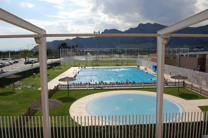 Piscina exterior del complejo con césped y zonas de descanso
