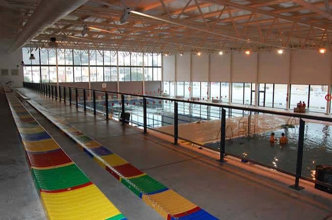 Interior de la piscina cubierta con carriles de natación y estructura metálica