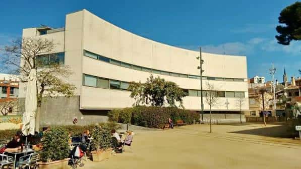 Vista general del edificio curvo de la biblioteca con jardín y personas en el patio