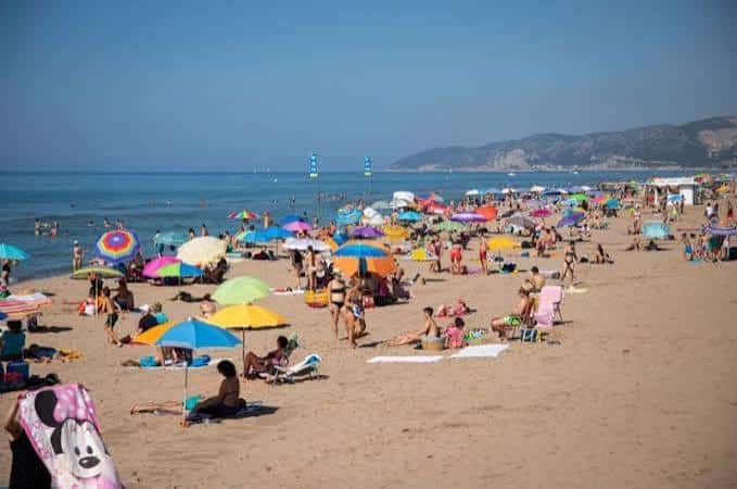 Playa del Baixador con bañistas y sombrillas bajo el sol