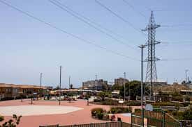 Área recreativa del parque con canchas deportivas y torres eléctricas al fondo