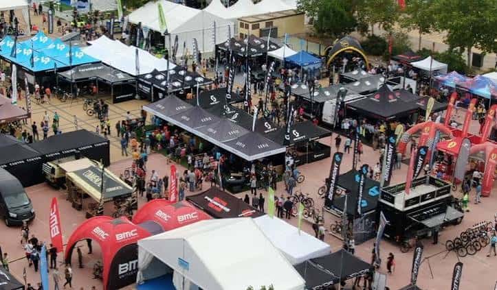 Plaza exterior del recinto durante un evento con stands de marcas y bicicletas