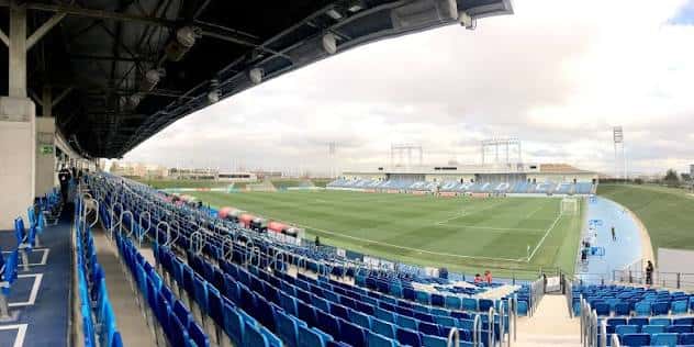 Vista panorámica del interior del estadio con gradas azules y campo de juego