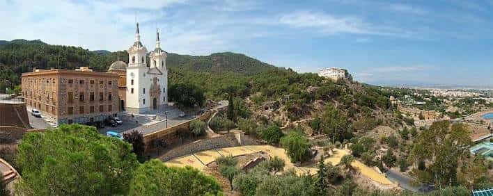Panorámica amplia del santuario desde una altura, mostrando su ubicación en la ladera y la ciudad al fondo
