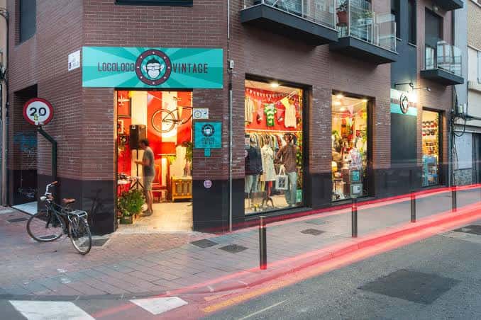 Fachada de la tienda Locoloco Vintage en Murcia con escaparate iluminado y bicicleta aparcada