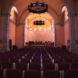 Interior del auditorio con butacas rojas dispuestas en filas hacia el escenario