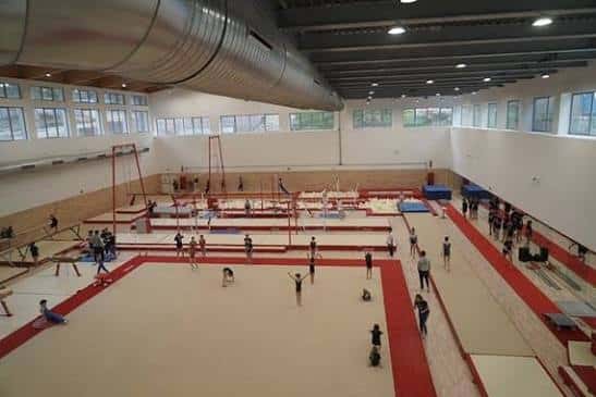 Pabellón de gimnasia artística con colchonetas rojas y equipamiento para entrenamiento