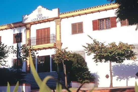 Vista completa del edificio desde el frente con escalinata y vegetación