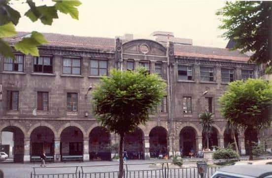 Fachada histórica de la Plaza de las Escuelas en Getxo con arcos y árboles