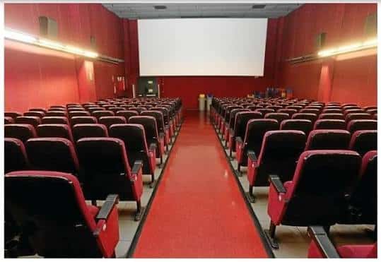 Vista frontal de la sala de cine con pantalla blanca y pasillo central