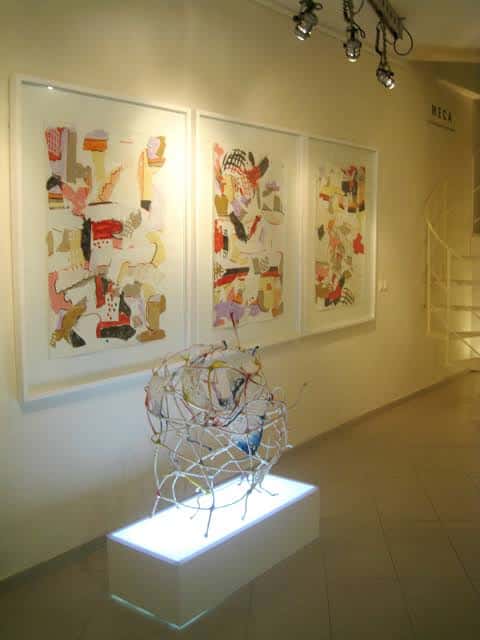 Exposición de arte abstracto con escultura iluminada en primer plano