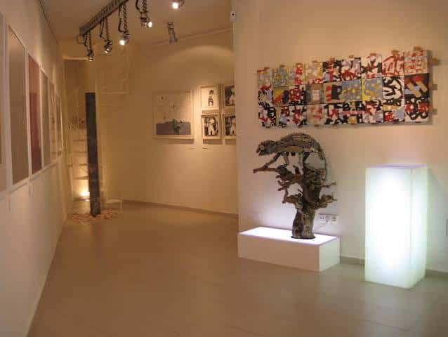 Sala de exposiciones con obra mural colorida y escultura orgánica