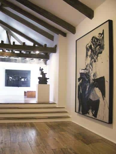Interior del museo con vigas de madera y obra abstracta en la pared