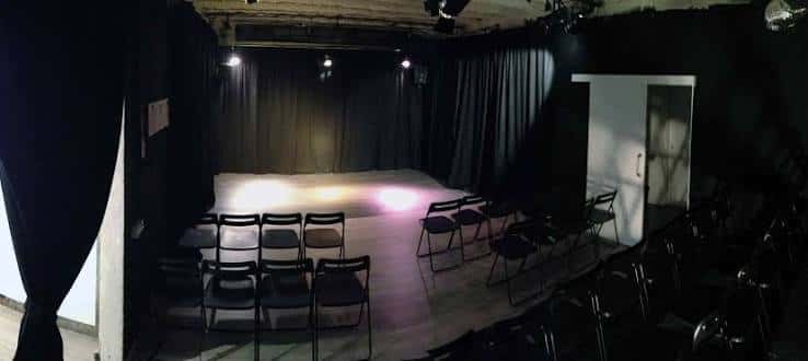 Escenario principal con cortinas negras y sillas plegables para eventos