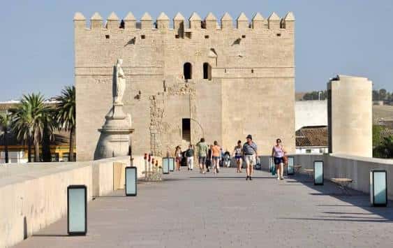 Entrada principal de la Torre de la Calahorra con visitantes caminando por el puente