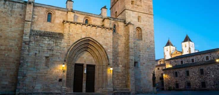 Fachada lateral de la catedral iluminada al atardecer con detalles góticos y adyacentes edificios históricos