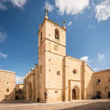 Vista frontal de la Concatedral de Santa María en Cáceres con su torre campanario bajo un cielo azul