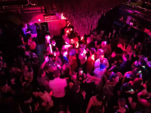 Escena nocturna en la pista de baile de Cuenca Club con iluminación rosa y ambiente festivo