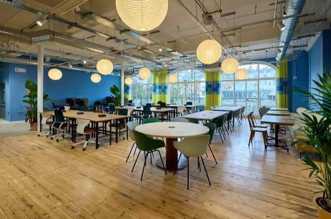 Vista general del espacio de coworking con mesas redondas y lámparas colgantes