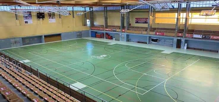 Interior del pabellón deportivo con pista de baloncesto y gradas