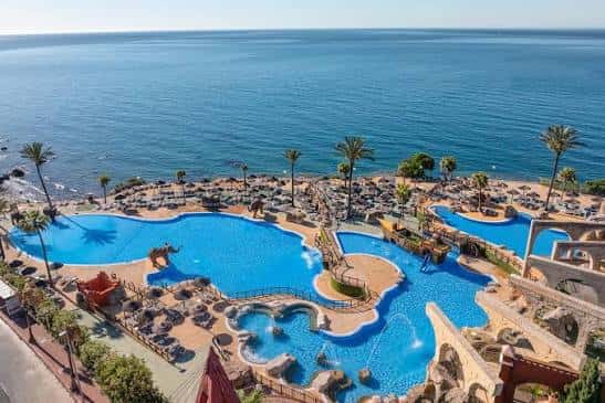 Piscina principal del resort frente al océano con tumbonas y palmeras