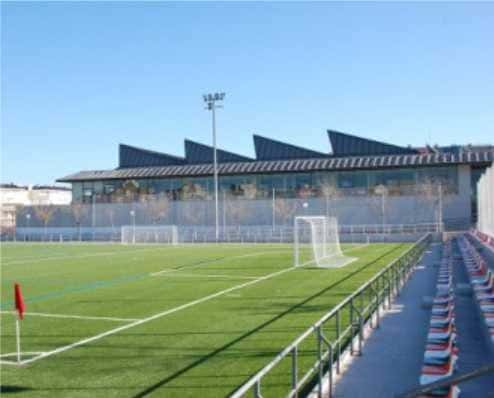 Campo de fútbol con gradas y estructura moderna bajo cielo despejado