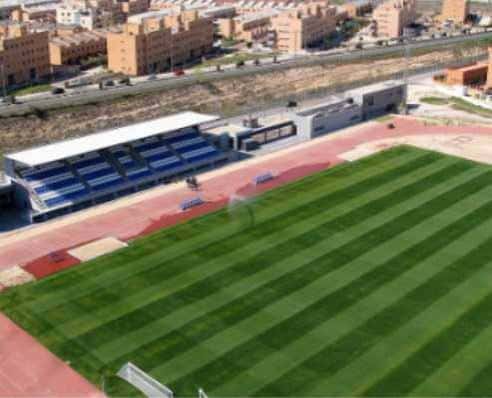 Vista aérea del estadio municipal con césped verde y tribunas azules