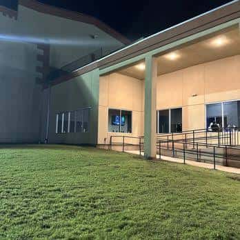 Fachada exterior del venue por la noche con rampa accesible y césped